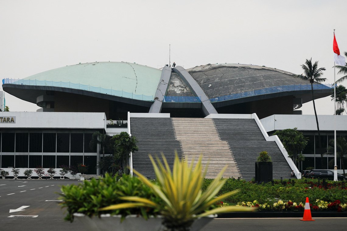 a worker walks on the roof of indonesian parliament building in jakarta