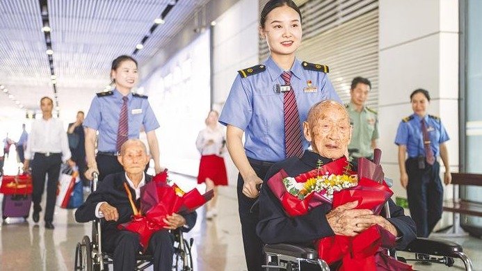 Passengers in the entire train car applaud as two centenarian war veterans return to Wuhan with honor